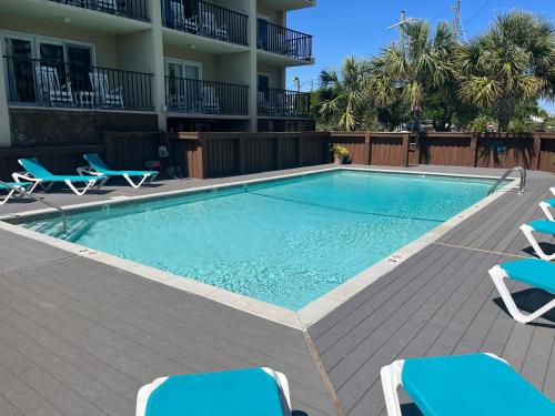 a swimming pool with lounge chairs and a building at Summer Sands - 401 by Sea Scape Properties in Wrightsville Beach