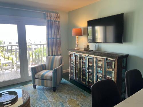 a living room with a television and a chair at Summer Sands - 406 by Sea Scape Properties in Wrightsville Beach
