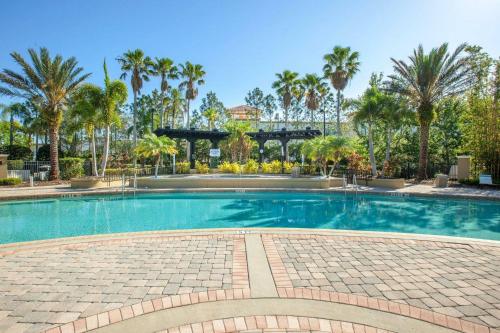 a large swimming pool with palm trees in the background at Modern Vacation Apartment with a Lake View in Orlando