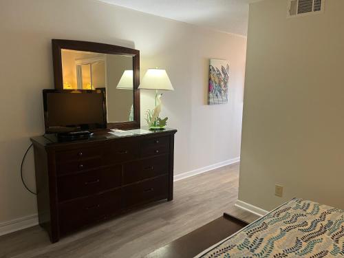 a bedroom with a dresser with a television and a mirror at Summer Sands - 402 by Sea Scape Properties in Wrightsville Beach