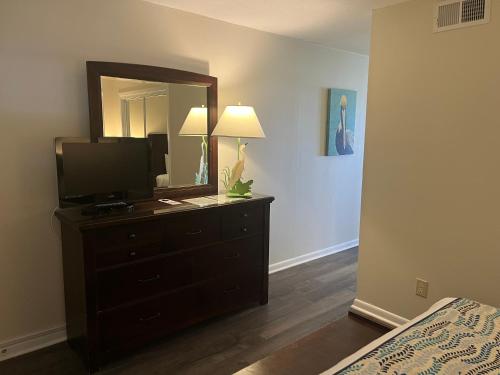 a bedroom with a dresser with a television and a mirror at Summer Sands - 408 by Sea Scape Properties in Wrightsville Beach