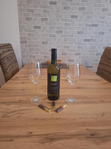 a bottle of wine sitting on a wooden table with two wine glasses at Apartman s terasou in Oščadnica