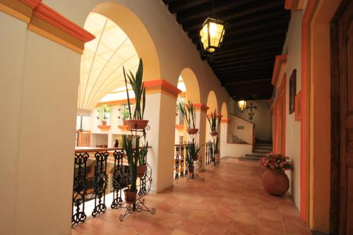 a hallway with arches and potted plants in a building at Hotel Ciudad Real Centro Historico in San Cristóbal de Las Casas