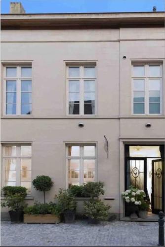 a white building with potted plants in front of it at Loft room heerenhuys in Eeklo