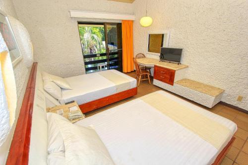 a room with two beds and a desk with a computer at Hotel Ciudad Real Palenque in Palenque