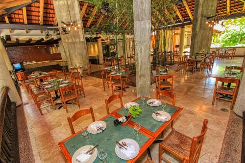 a dining room with tables and chairs in a restaurant at Hotel Ciudad Real Palenque in Palenque
