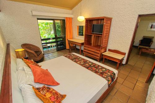 a bedroom with a bed and a desk and a television at Hotel Ciudad Real Palenque in Palenque