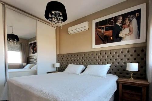 a bedroom with a large bed with a picture on the wall at Verão dos Sonhos no Condomínio Dubai Resort in Capão da Canoa