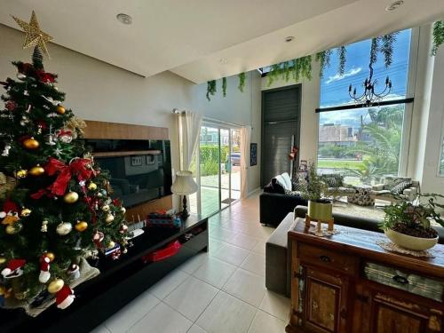 a living room with a christmas tree in the middle at Verão de Luxo no Condomínio Condado de Capão in Capão da Canoa