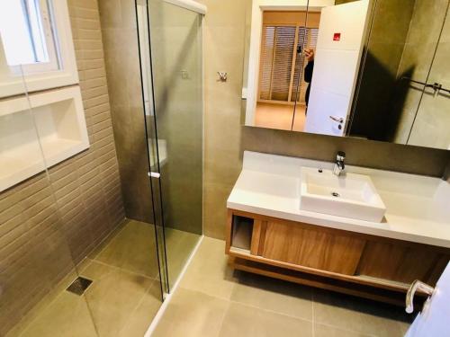 ein Badezimmer mit Waschbecken und Dusche in der Unterkunft Casa de Luxo Decorada no Condomínio La Plage in Xangri-lá