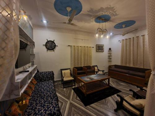 a living room with couches and chairs and a clock at Draupadi kunj -a place of peace in Rāipur