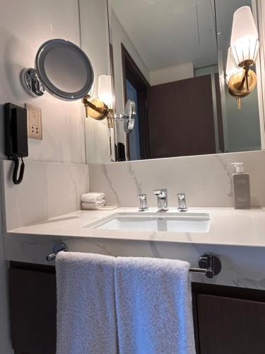 a bathroom with a sink and a mirror and towels at Address Residence Bahrain in Rayyā