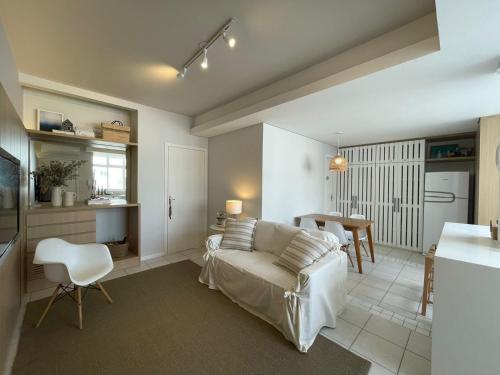 a living room with a white couch and a kitchen at Beira-Mar de Atlântida: Conforto Completo in Xangri-lá
