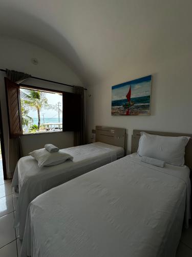 two beds in a room with a window at Pousada Amor a Mar Pé na Areia na Praia de Barreiras, Icapuí in Icapuí