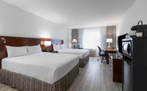 a hotel room with two beds and a television at Le Nouvel Hotel in Montréal