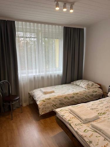 a bedroom with two beds and a window and a chair at Apartament Korczaka in Suwałki