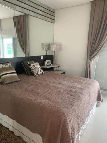 a bedroom with a large bed and a table at Verão Perfeito no Condomínio Ventura Club in Xangri-lá