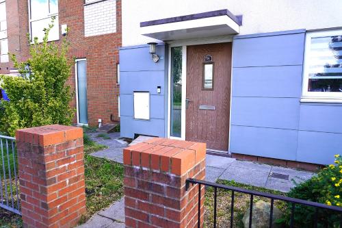 a brick pillar in front of a house with a blue door at Luxury Rooms - Pick a Room - Free Parking & Kitchen Access, Near Etihad Stadium, The Coop Live & Piccadilly Station, Manchester in Manchester
