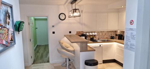 a kitchen with white cabinets and a sink and a clock at NEW 3 bedrooms Flat in Ashford near Heathrow in Ashford