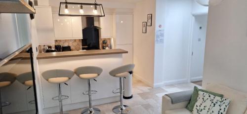 a living room with stools and a kitchen at NEW 3 bedrooms Flat in Ashford near Heathrow in Ashford