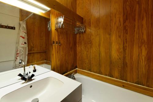 La salle de bains est pourvue d'un lavabo blanc et de murs en bois. dans l'établissement Résidence La Maison Tresallet - Studio au coeur de la station MAE-9324, à Aime La Plagne