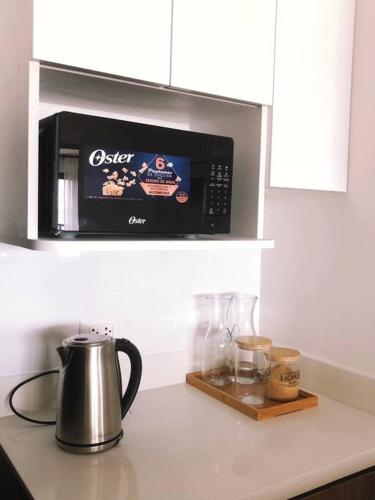 a microwave above a kitchen counter with a kettle and glasses at Apartment with Panoramic & Ocean View in Lima