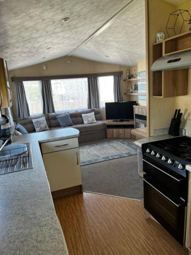 a kitchen and living room with a couch and a stove at 118 holiday resort unity pet friendly caravan brean sands in Berrow