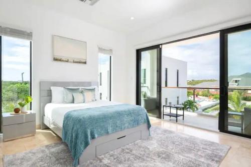 a bedroom with a large bed and large windows at Villas private pool Long Bay Hills, Turks and Caicos Islands in Long Bay Hills