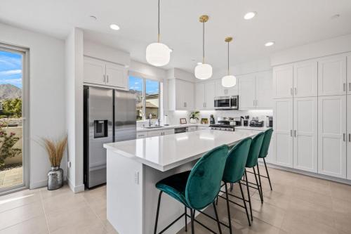 a kitchen with white cabinets and a large island with green chairs at PGA West 65 - 3 bdrm w/Loft, Sleeps 8, Pool, Gym in La Quinta
