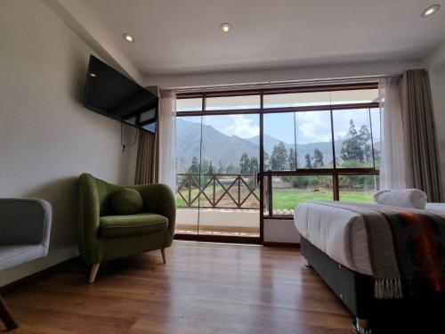 a bedroom with a bed and a chair and a large window at Flores de la Villa in Huaran