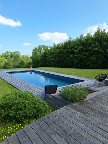 - une piscine avec 2 chaises sur une terrasse en bois dans l'établissement La Cour Marmion, à Valsemé