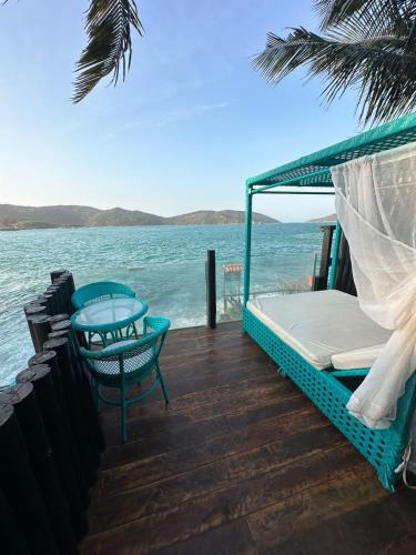 a bed and a table on a deck overlooking the ocean at Pousada Vista Grega in Arraial do Cabo