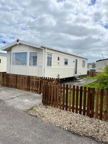 a white house behind a wooden fence at 118 holiday resort unity pet friendly caravan brean sands in Berrow