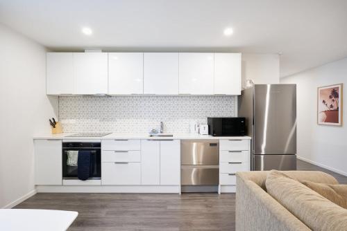 a kitchen with white cabinets and stainless steel appliances at Modern Central Apartment, Flexible Bed Options in Dunedin