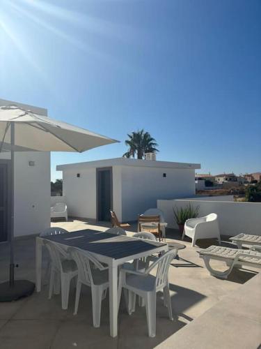 a patio with a table and chairs and an umbrella at Quinta por do sol in Quelfes