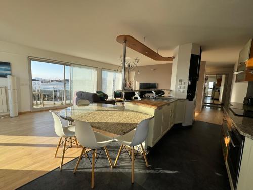 une cuisine avec une table en verre et des chaises blanches dans l'établissement Appt 4 pers, centre-ville tout à pieds, plage 300m, aperçu mer, très calme parking privé, possibilité garage et location vélos électriques, à Royan