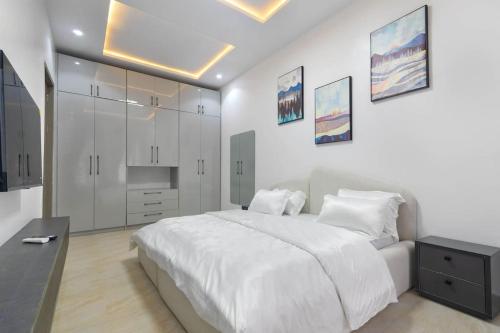 a white bedroom with a large white bed and cabinets at Elegant 3 Bedroom Terrace Duplex in Lekki in Ikate