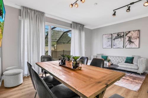 a dining room and living room with a wooden table and chairs at 3BD/3BA Windsor Hills, 10 min to Disney in Orlando