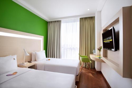 MaxOneHotels at Belstar Belitung في تانجونج باندان: غرفة فندقية بسريرين وجدار أخضر