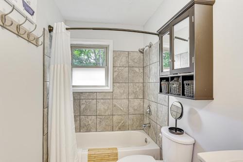 een badkamer met een bad, een toilet en een raam bij Dandys Getaway with Fire Pit and Yard in Henderson in Henderson