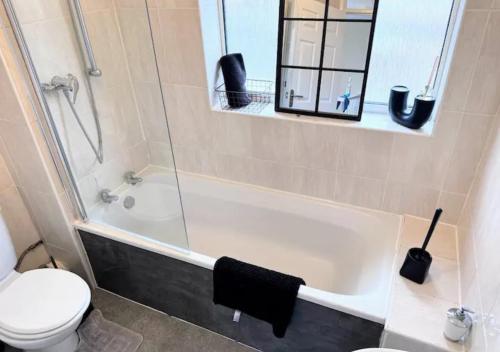 a bathroom with a tub and a toilet and a mirror at Luxurious Retreat 4bd in Maidstone in Kent