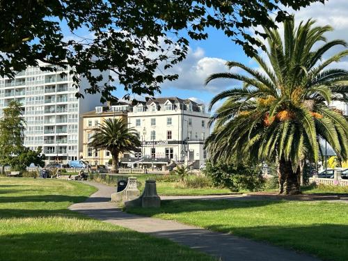 a palm tree in a park with a building at Clarence Quarters Vintage Seafront Guest House in Portsmouth