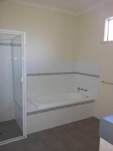 a white bathroom with a shower and a tub at Karma Waters Beach House, 100m from beach in Middleton