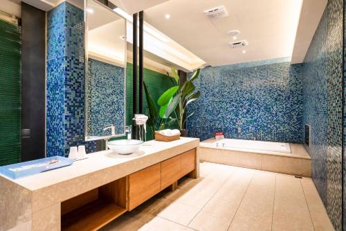 a bathroom with a sink and a tub with blue tiles at Aquarius Motel in Taichung