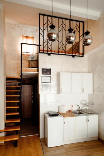 a kitchen with white cabinets and a staircase to a bunk bed at CROWNE Stan11550 Sopstveno Parking Mesto in Lazarevac