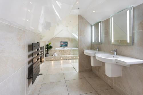 a bathroom with two sinks and a tub at Aphrodites Group - Luxury Hot Tub Suites in Central Lake District! in Bowness-on-Windermere