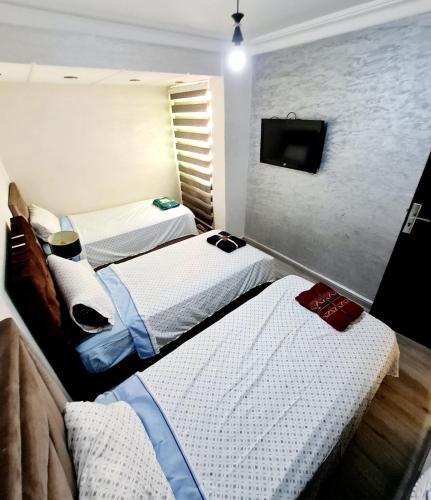 a room with two beds and a tv in it at Luxury Apartment Fes - Family Suites in Fès