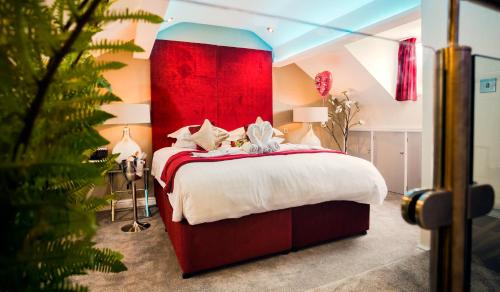 a bedroom with a large bed with a red headboard at Aphrodites Group - Luxury Hot Tub Suites in Central Lake District! in Bowness-on-Windermere