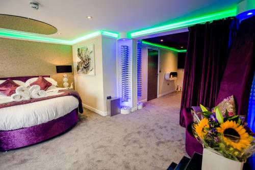 a hotel room with a bed and flowers in it at Aphrodites Group - Luxury Hot Tub Suites in Central Lake District! in Bowness-on-Windermere