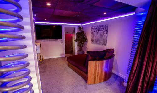 a room with a couch and a wall with blue lights at Aphrodites Group - Luxury Hot Tub Suites in Central Lake District! in Bowness-on-Windermere